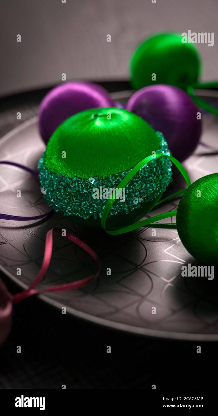 Green and purple Christmas baubles on a black plate Stock Photo