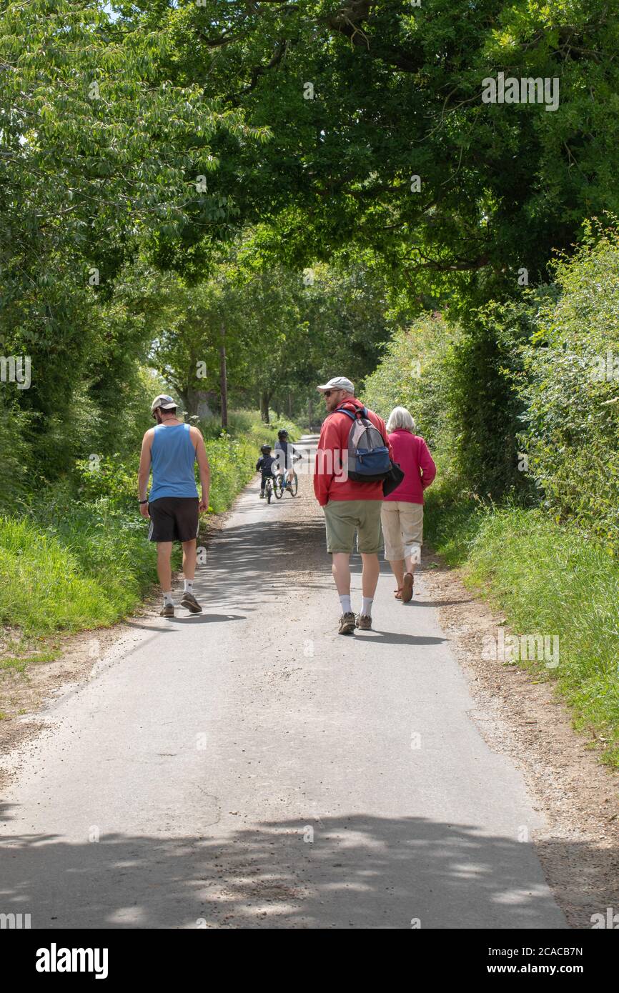 Adults, grandmother, father and uncle, watching over two grandsons on their bicycles riding along a  quiet safe country road. Norfolk. East ANGLIA. UK. Stock Photo