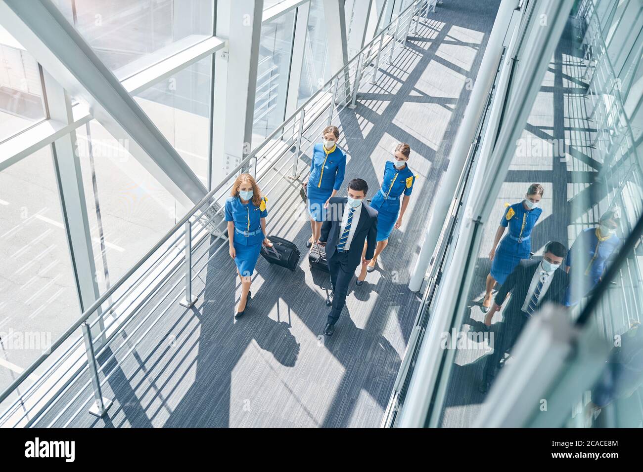 Thoughtful cabin crew pulling their suitcases in the airport Stock