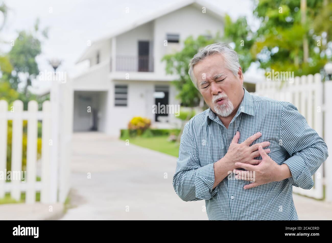 Asian man having chest painful heart attack at outdoors home park - heart disease concept Stock Photo