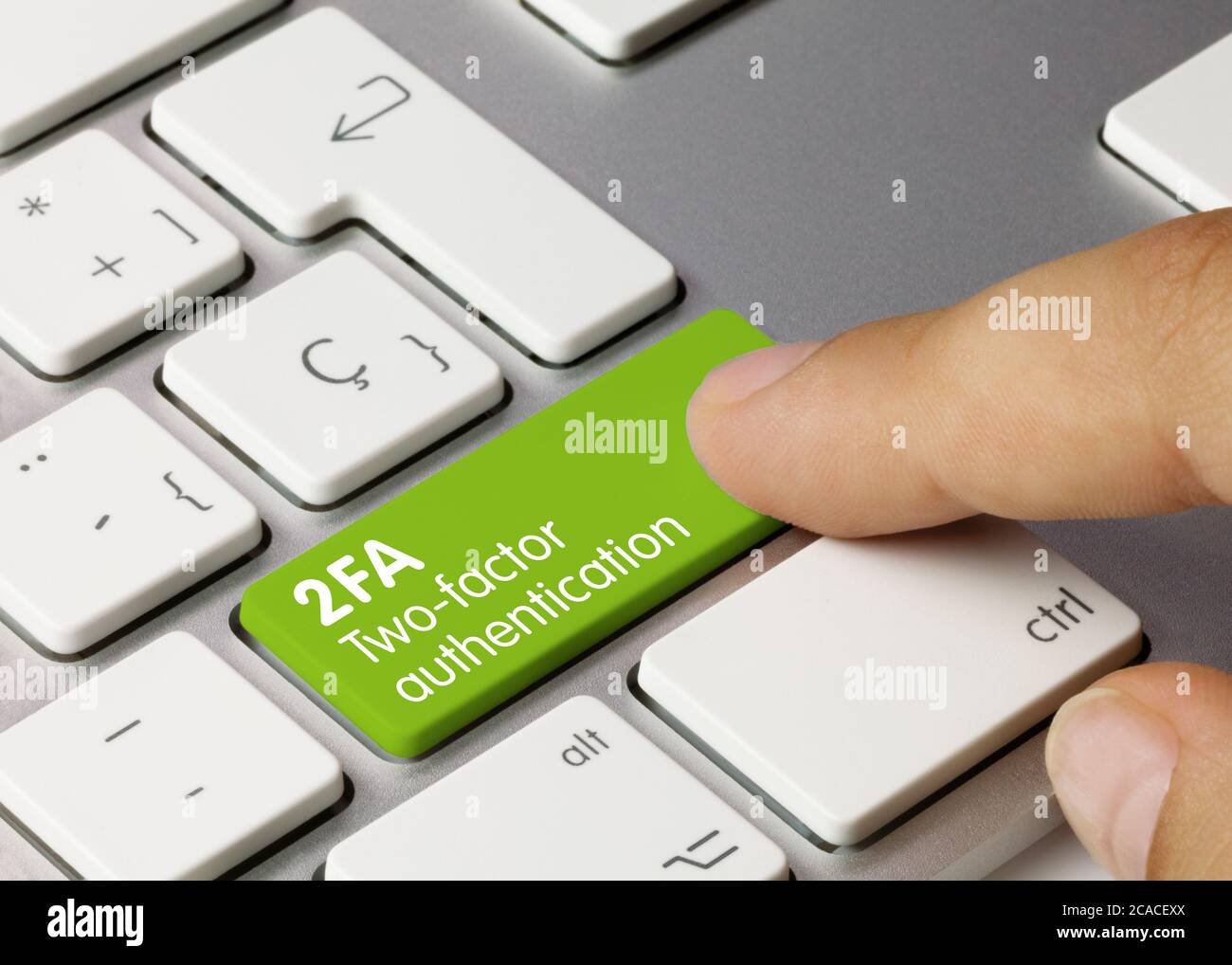 2FA Two-factor authentication Written on green Key of Metallic Keyboard. Finger pressing key Stock Photo