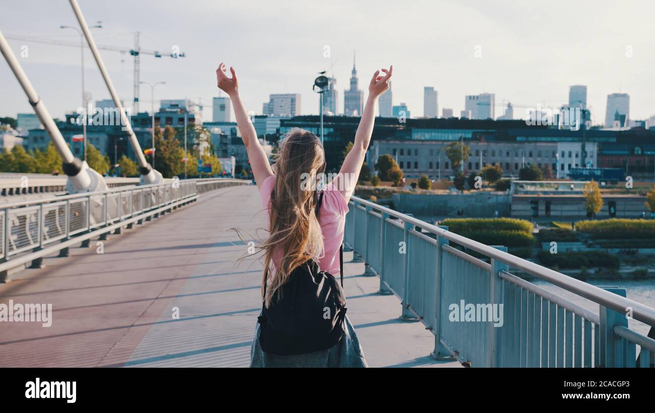 Young woman with backpack. Freedom concept. Rising hands in the air. Pedestal up follow shot. High quality photo Stock Photo