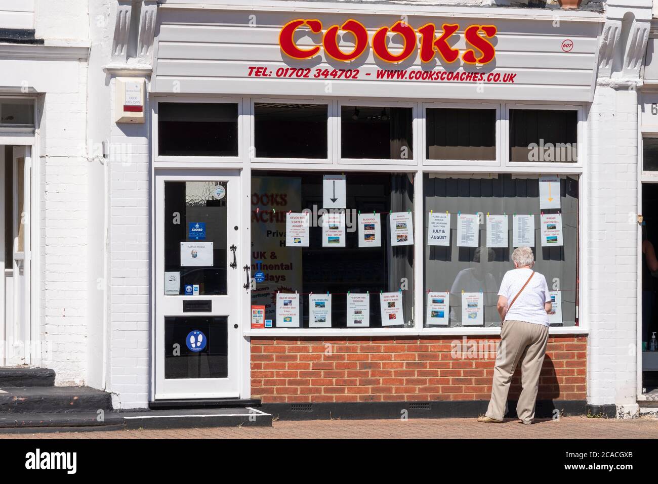 Cooks Coaches office in Westcliff on Sea, Essex, UK, with senior female looking at the window display. Holidays and day excursions travel business Stock Photo