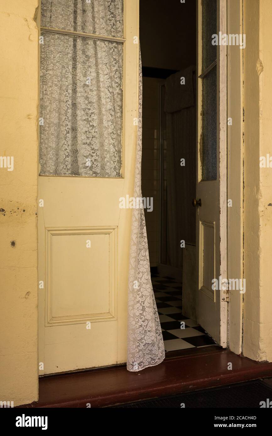 Curtain blowing in open doorway to a bedroom in an old Queenslander style house with French doors Stock Photo