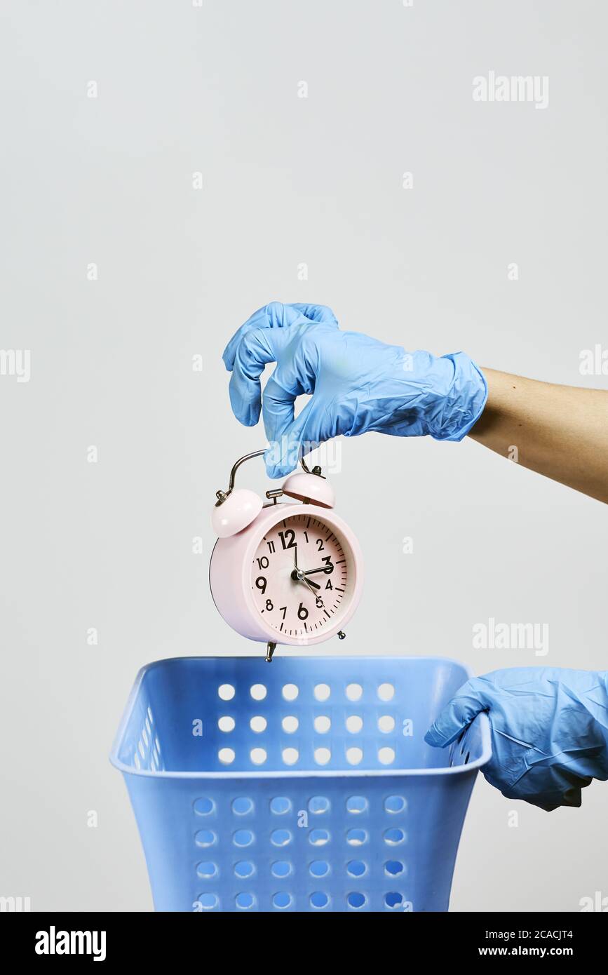 Vertical shot of a hand throwing alarm clock into a rubbish bin lost