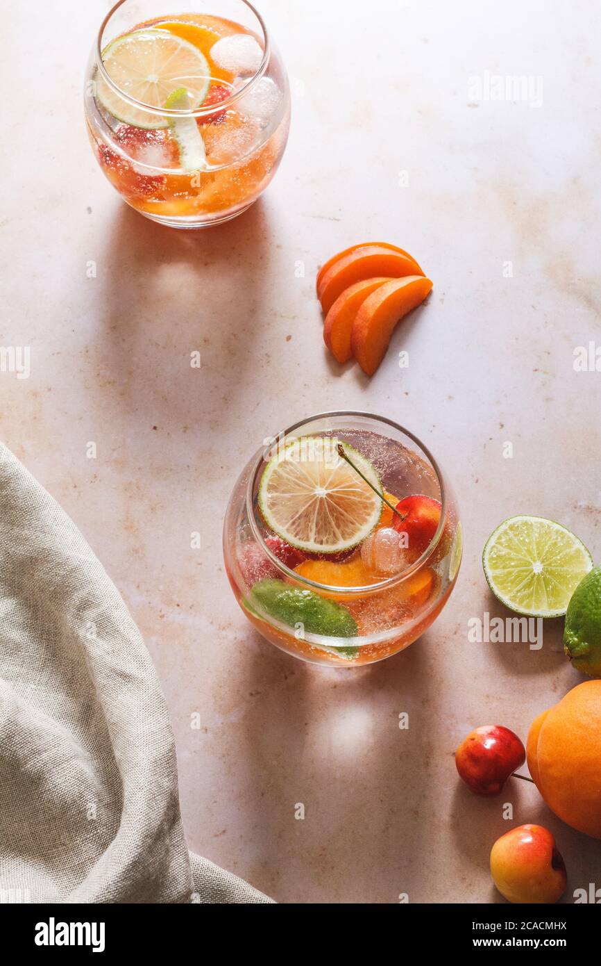 Cherry and apricot gin and tonic with lime and fruit garnishes Stock Photo