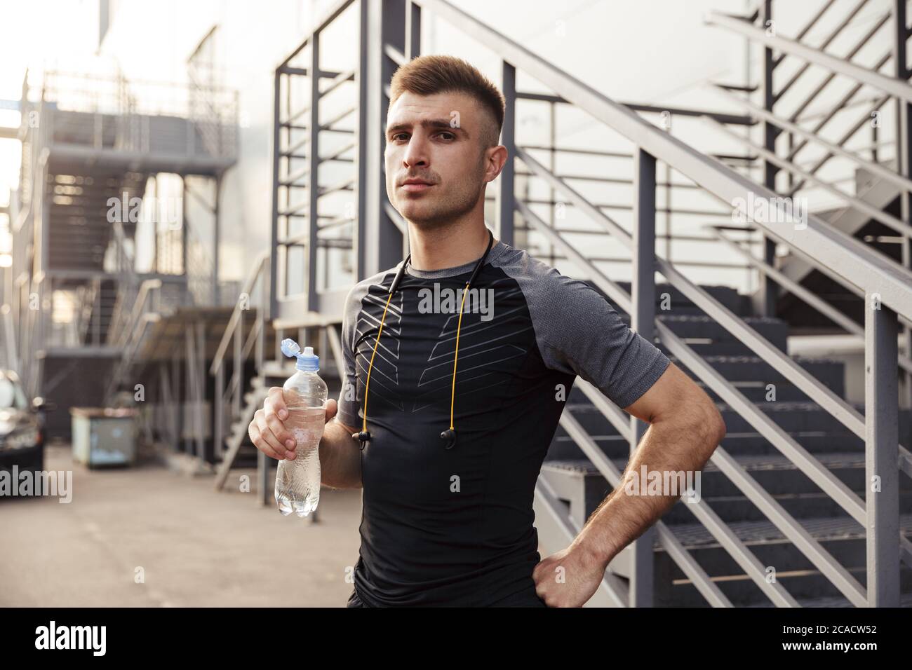 Image of unshaven caucasian sportsman drinking water while working out
