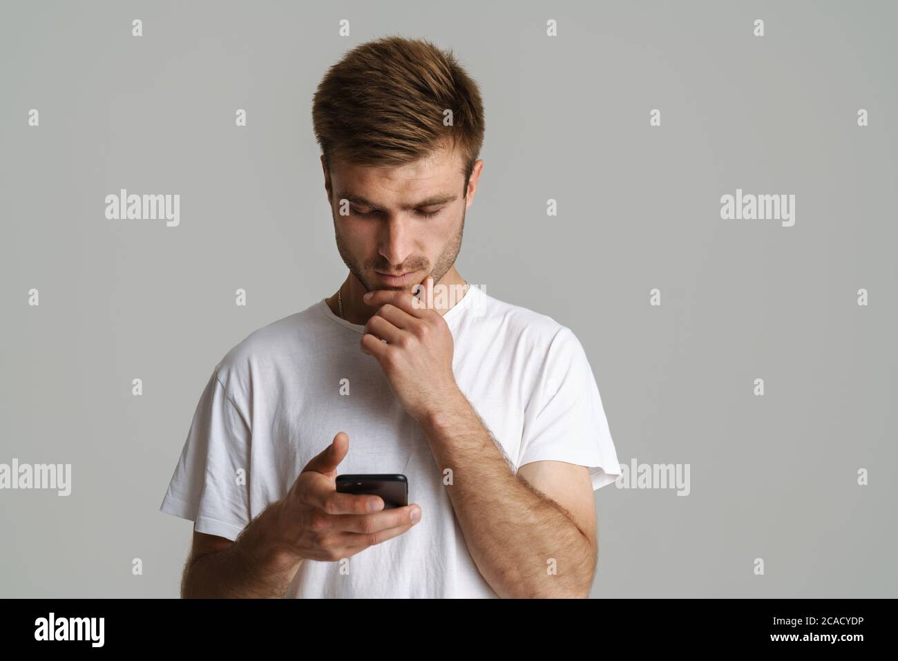 Portrait of handsome brooding man thinking and using mobile phone ...