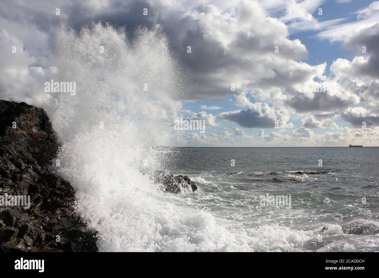 crashing wave against a dark cloud Stock Photo