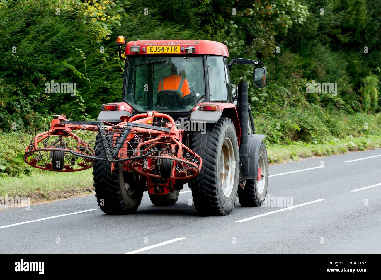 A tractor with a hay rake, on a country road, Warwickshire, UK Stock ...