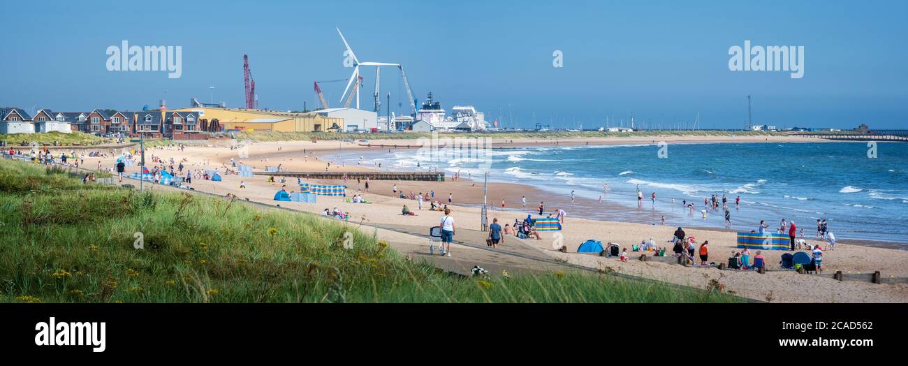 British seaside on sunny summer day, panorama view of families on sand at Blyth beach on the Northumberland coast of the North of England Stock Photo