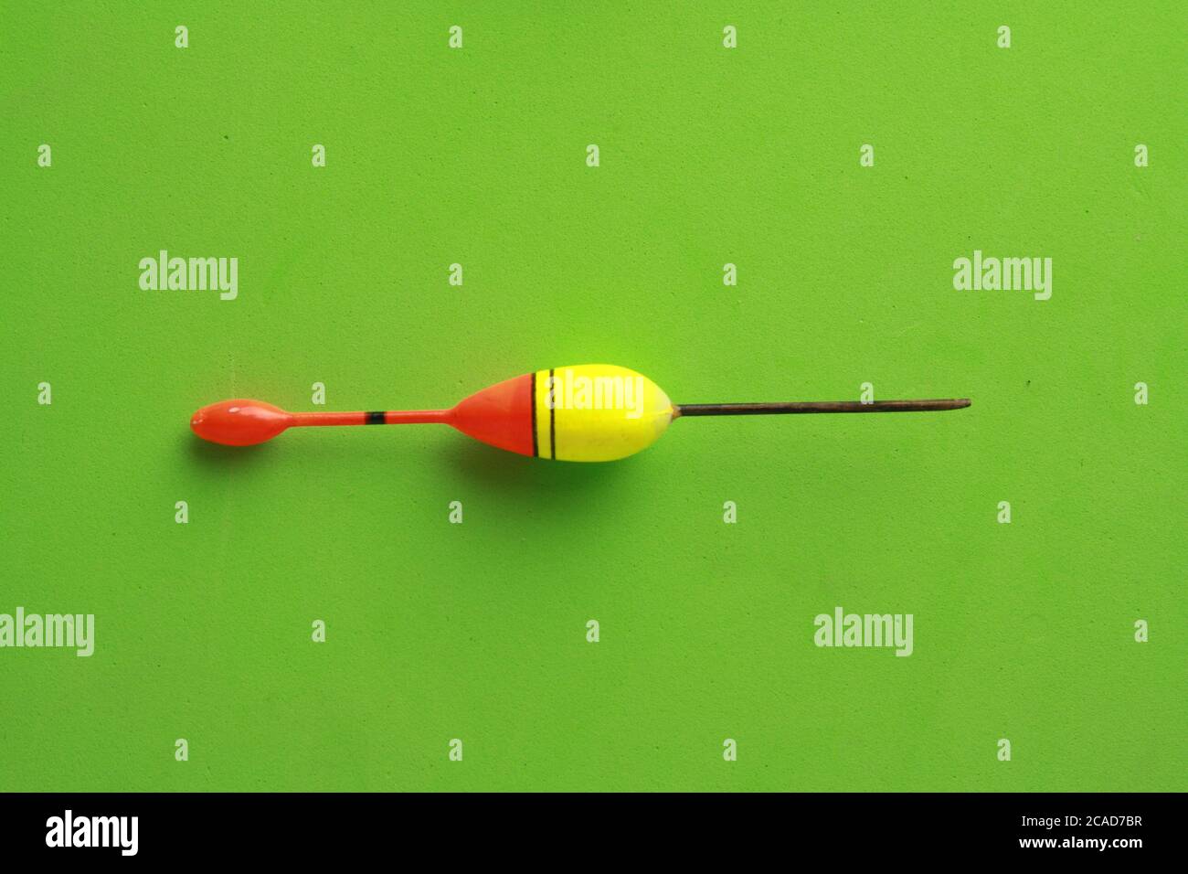 Top view of a colorful fishing rod bobber on a green background