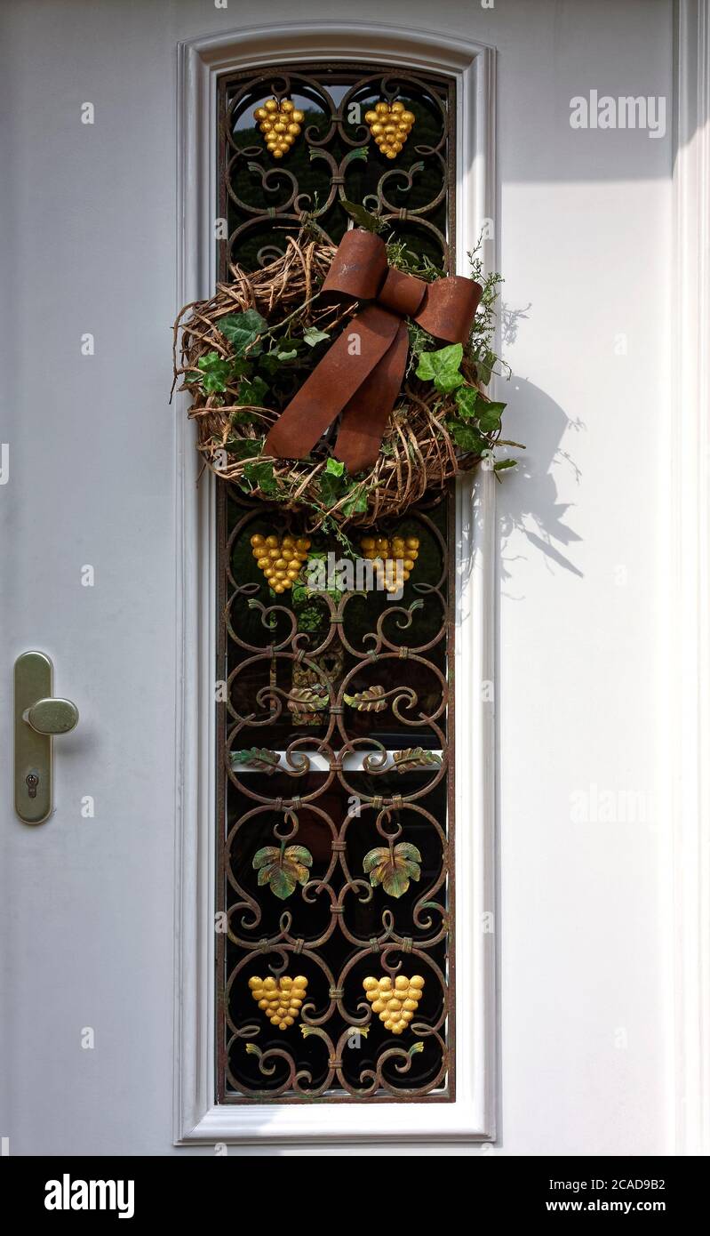 exterior door, cream color, gold grape bunches, leaves, decorative metal grill, grapevine wreath, grapevine decoration. Mosel, Europe, Moselle Valley, Stock Photo