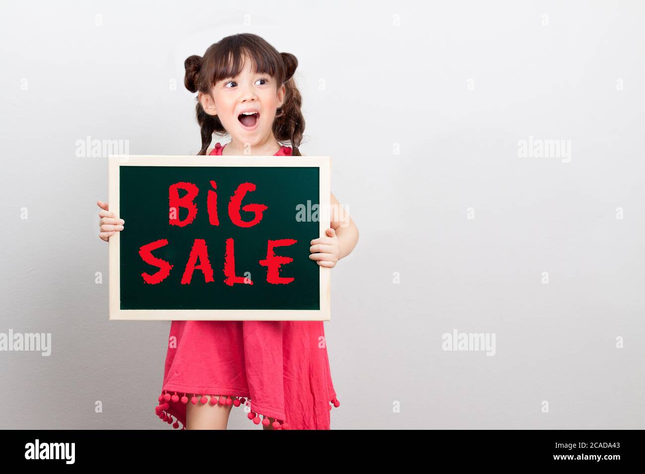 big sale discount for item in shopping mall promotion on end of year concept : adorable girl act surprise face holding chalk sign board , big sale Stock Photo