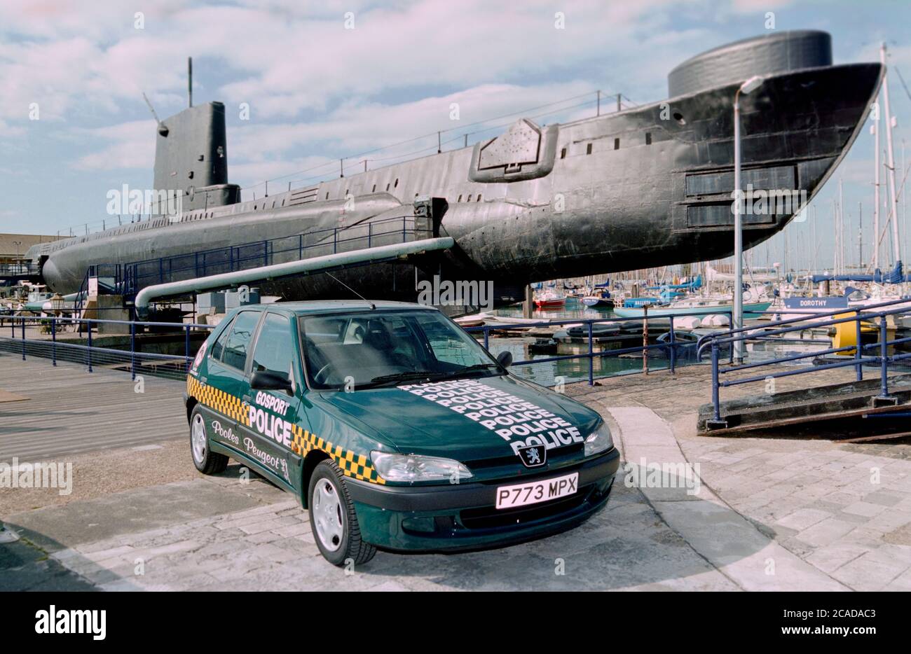 A sponsored community police car on display at the Royal Navy Submarine Museum at Gosport, Hampshire, England, UK - museum exhibit HMS Alliance is in the background. Stock Photo