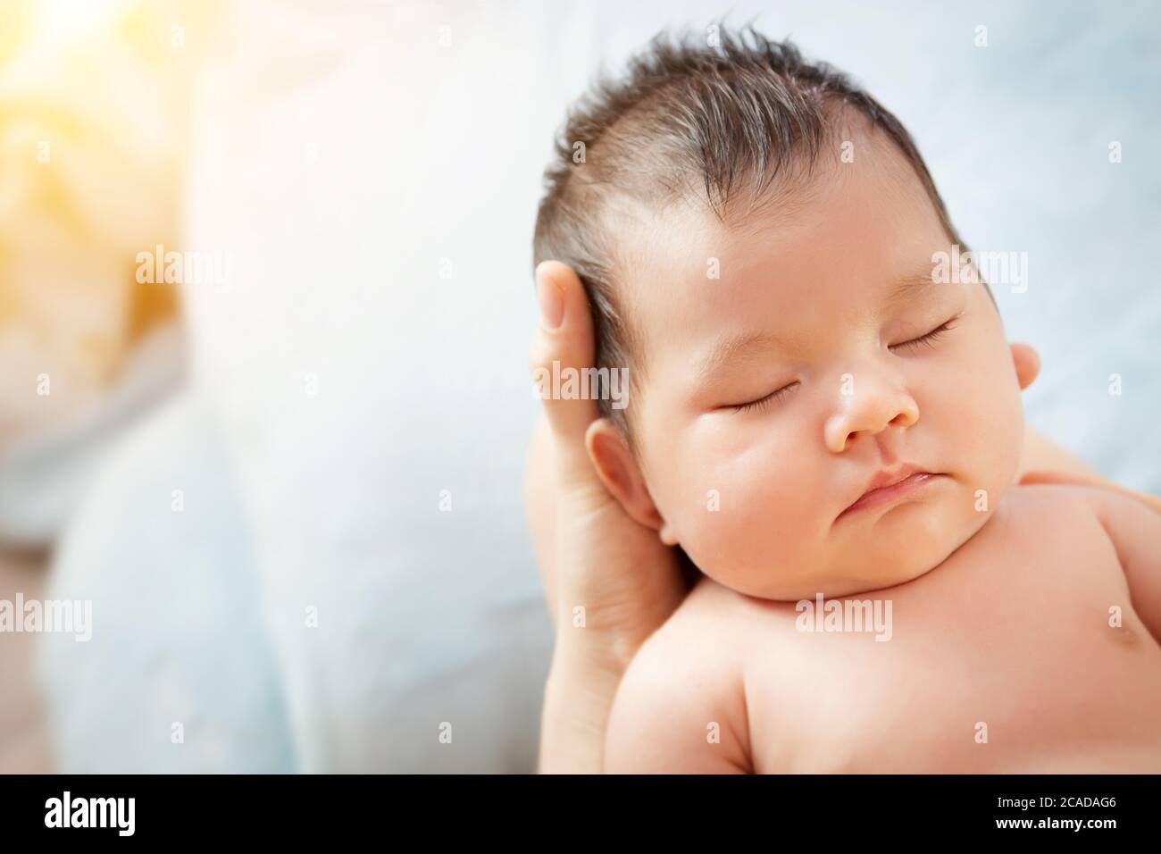love and relationship in family. Mother holding head of her beautiful newborn daughter in hands. Loving mother hand holding cute sleeping newborn baby Stock Photo