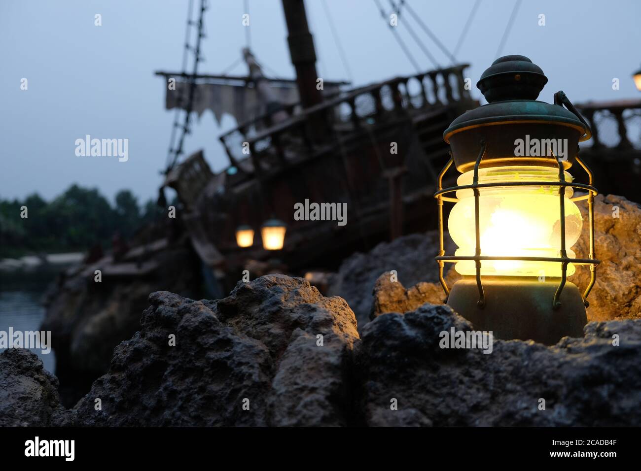close up retro beacon light on grey stones. Blurred dark pirate ship wreckage and dark sky background Stock Photo