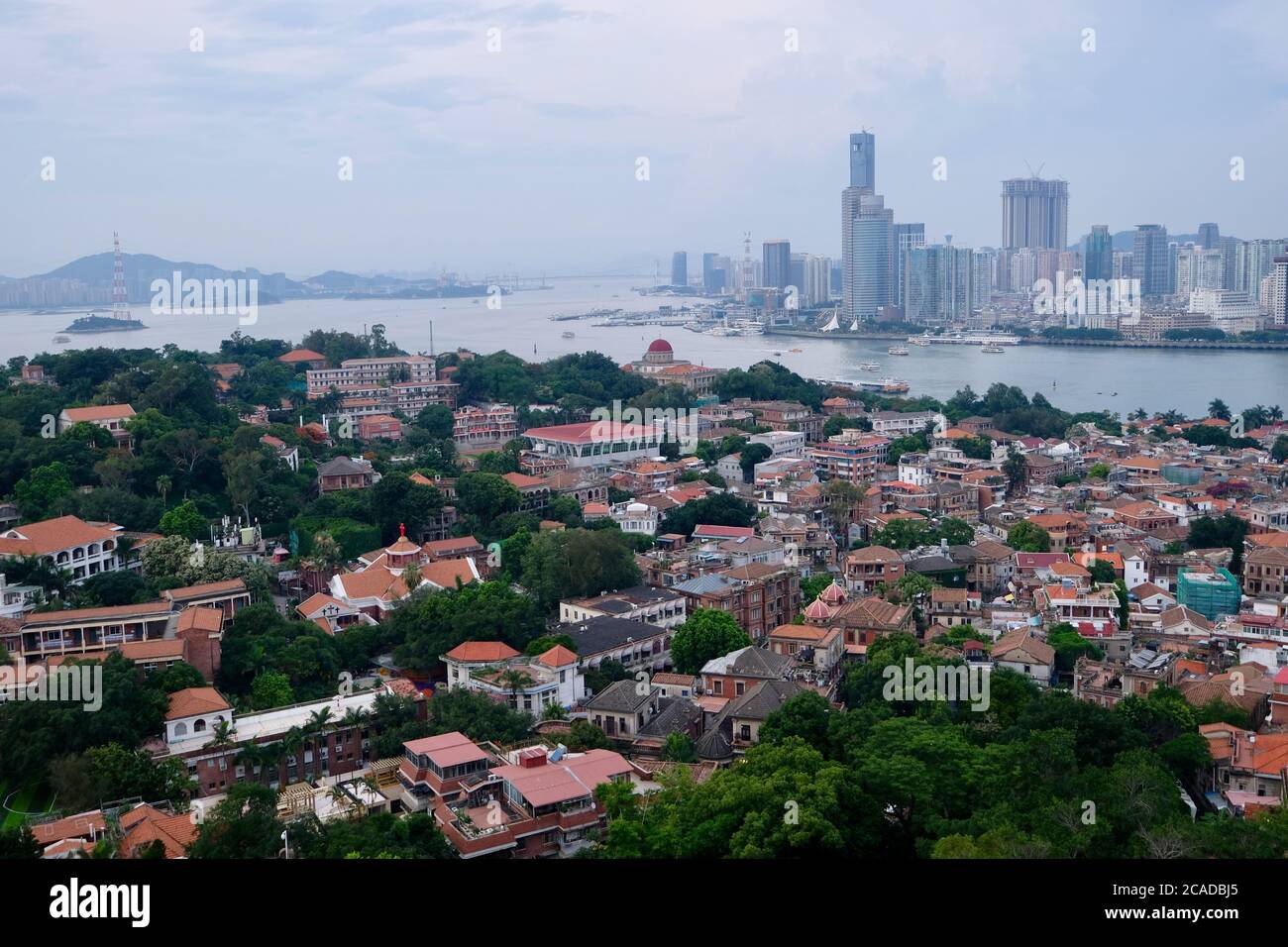 aerial view of Gulangyu(Kulangsu) Island in Xiamen,Fujian,China. Houses and trees. Modern skyscrapers on the other side of the river. Stock Photo