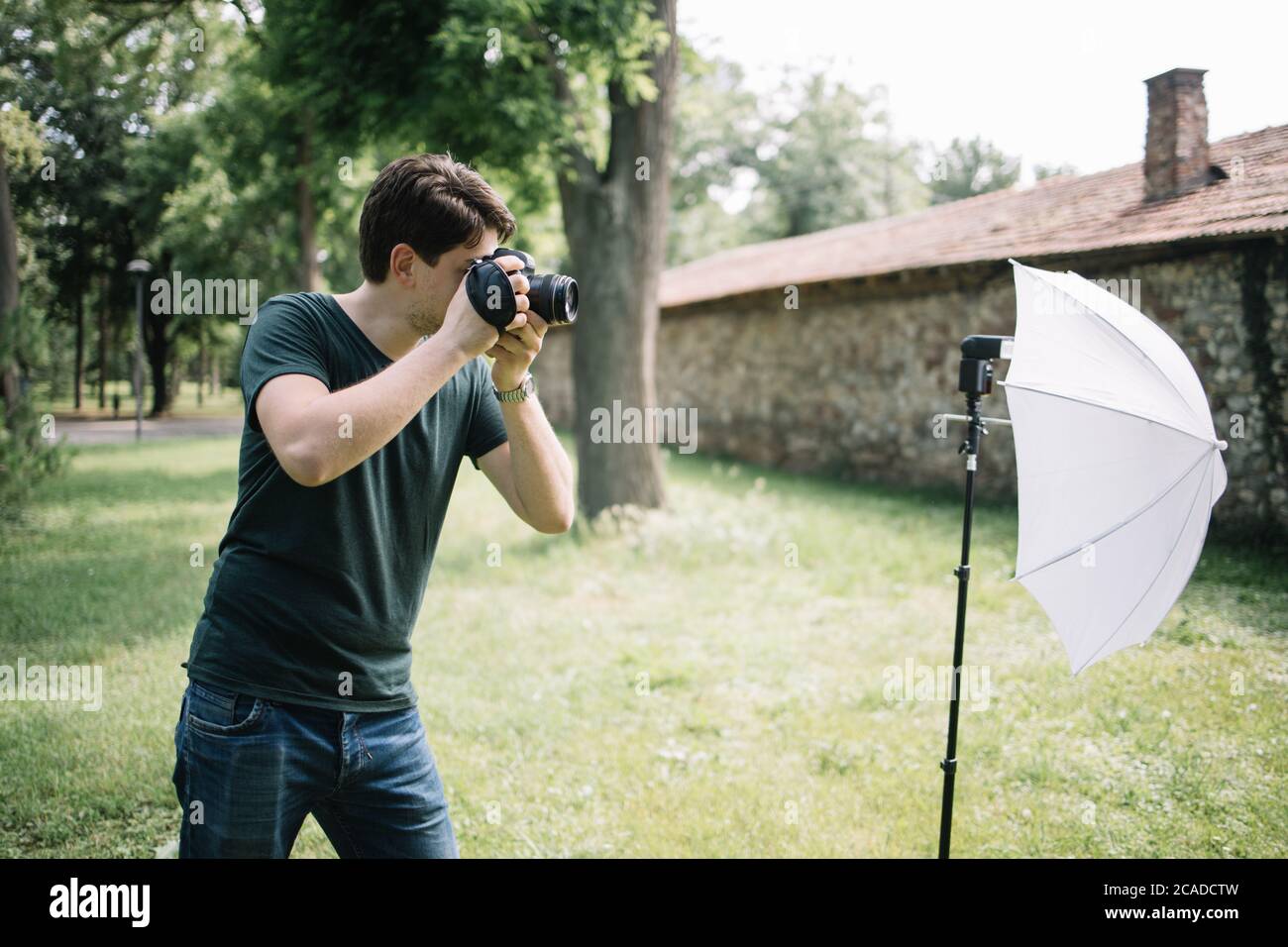 Side view of man holding professional camera and taking photos Stock Photo