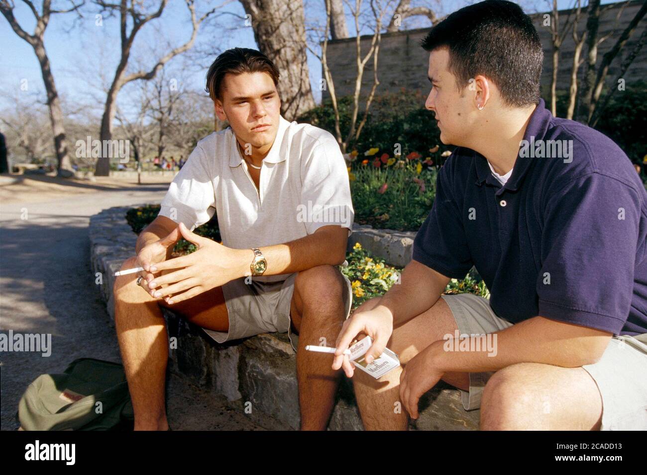 Austin Texas USA: Teen boys (17-18 years old) smoking cigarettes outside in  public park in Austin, Texas. Model Release ©Bob Daemmrich Stock Photo