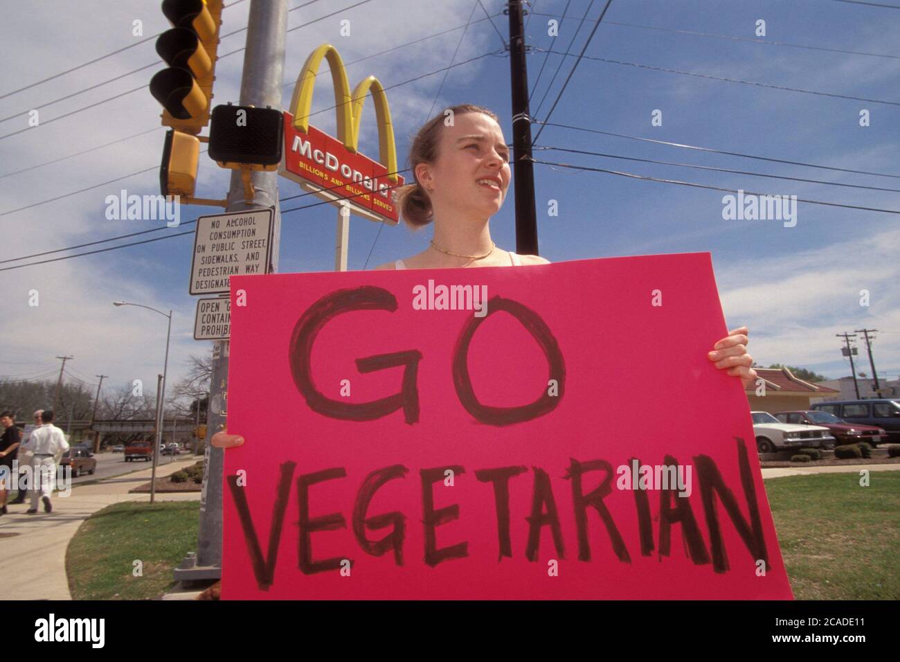 Austin Texas USA: Teen animal rights activist holds a 'Go Vegetarian' sign while picketing outside a McDonald's fast food restaurant at a busy intersection. ©Bob Daemmrich Stock Photo