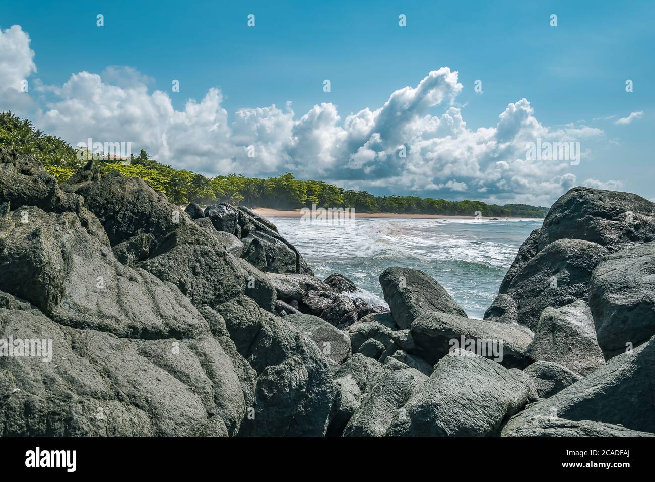 Black dark boulders lying on a beach after the coast in Axim Ghana West Africa Stock Photo