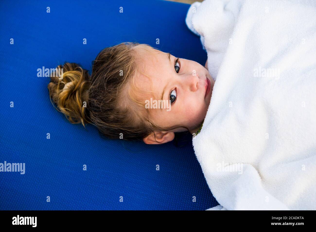 portrait of 3 year old girl wrapped in white towel Stock Photo