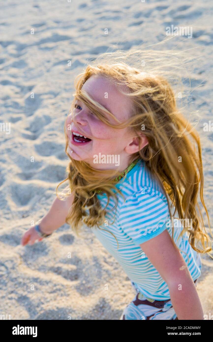 laughing 3 year old girl running in the sand Stock Photo