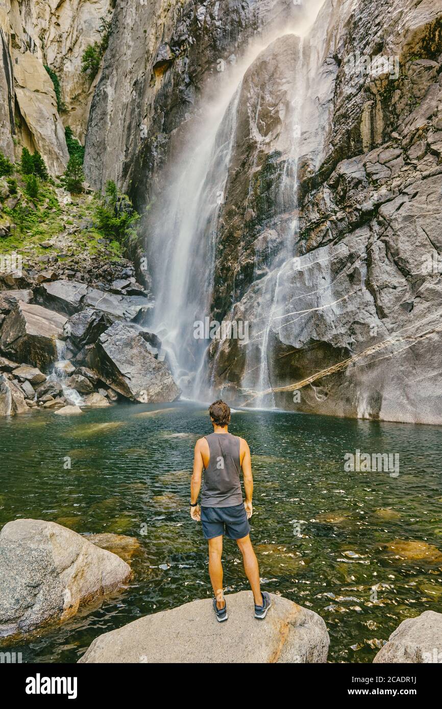 Young man standing on boulder, observing Yosemite Falls. Stock Photo