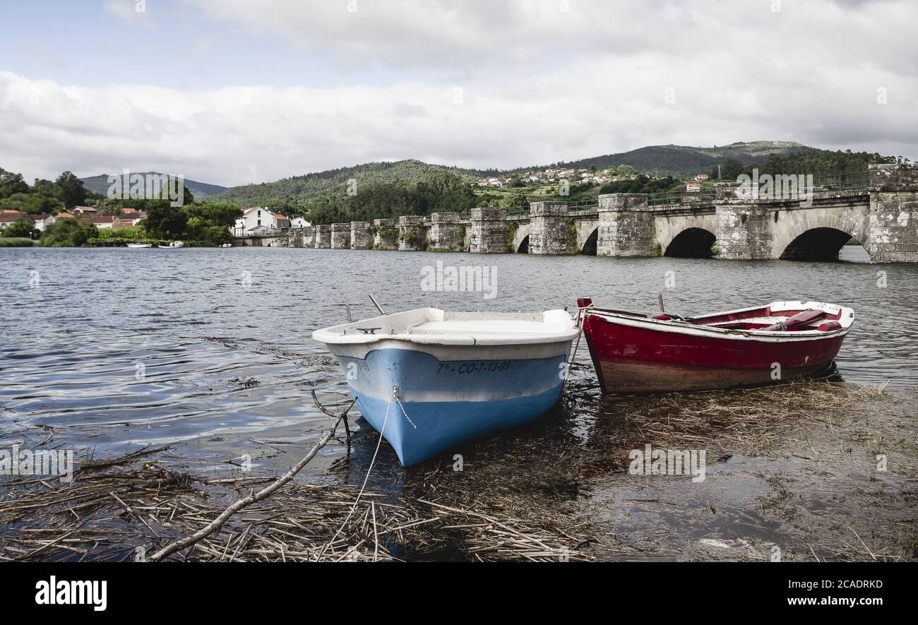 NOYA, SPAIN - Aug 13, 2018: Pequenos botes en el rio Tambre con el puente Nafonso al fondo. Ria de Noya, Galicia, Espana. Stock Photo