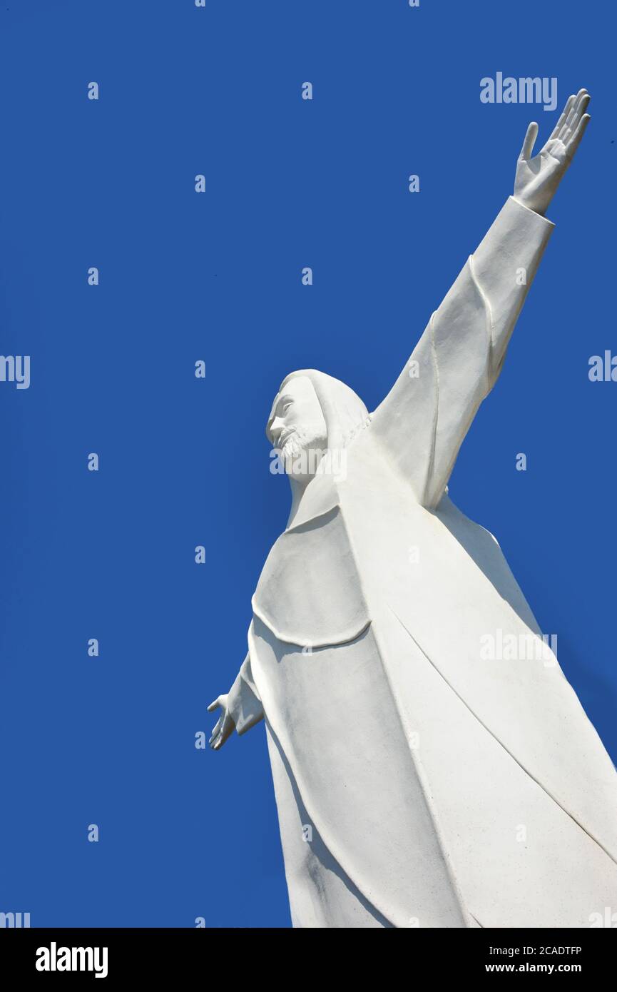 Christ of the Ozarks statue stands against a vivid blue sky.  Arms are open wide offering confort and peace. Stock Photo