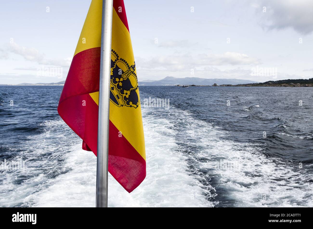 OCEANO ATLANTICO, COSTA DE GALICIA, SPAIN - Aug 07, 2018: Bandera de Espana situada en la popa de un barco a motor que navega por la costa gallega en Stock Photo