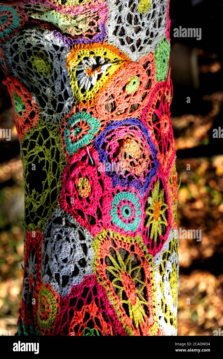 Park in Eureka, Springs has decorated tree trunks with old crocheted afghans recycling them.  This pattern has flowers in multiple colors. Stock Photo