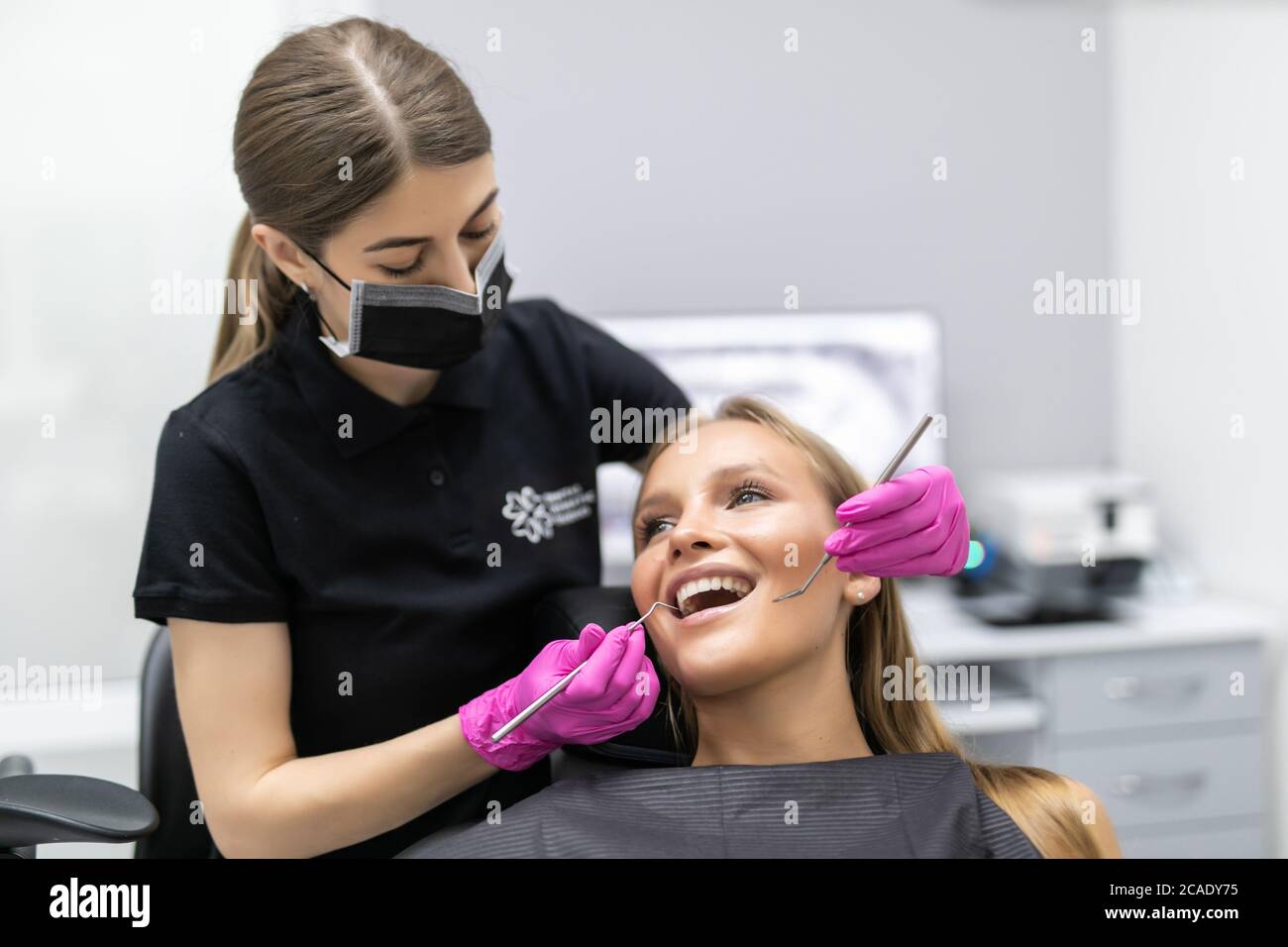 Young woman having dental check-up in dentist's office, smiling, looking at camera. Stock Photo