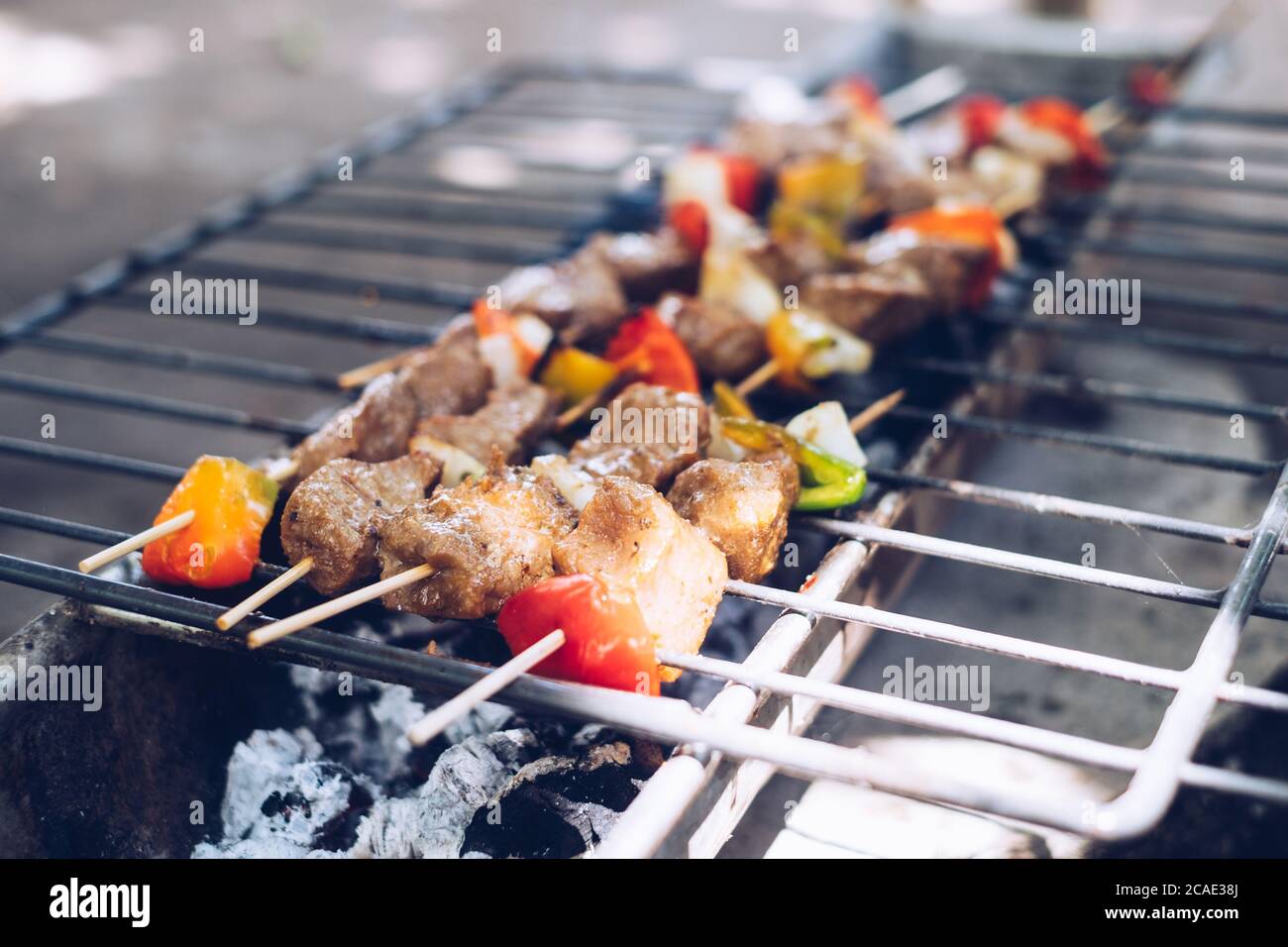 Grilling sticks of Kebab - meat and vegetables in skewers, over hot charcoal fire. Selective focus. Stock Photo