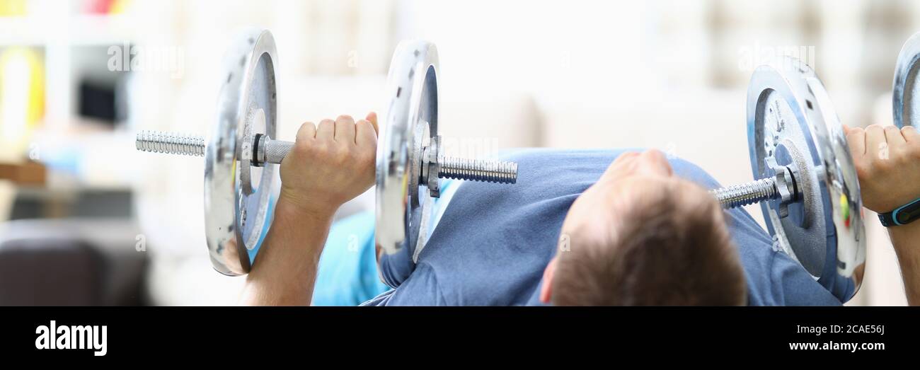 Man doing strength exercises with dumbbells home Stock Photo