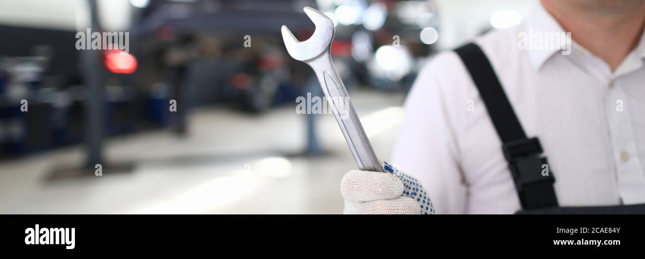 Man in uniform is standing in workshop with wrench Stock Photo