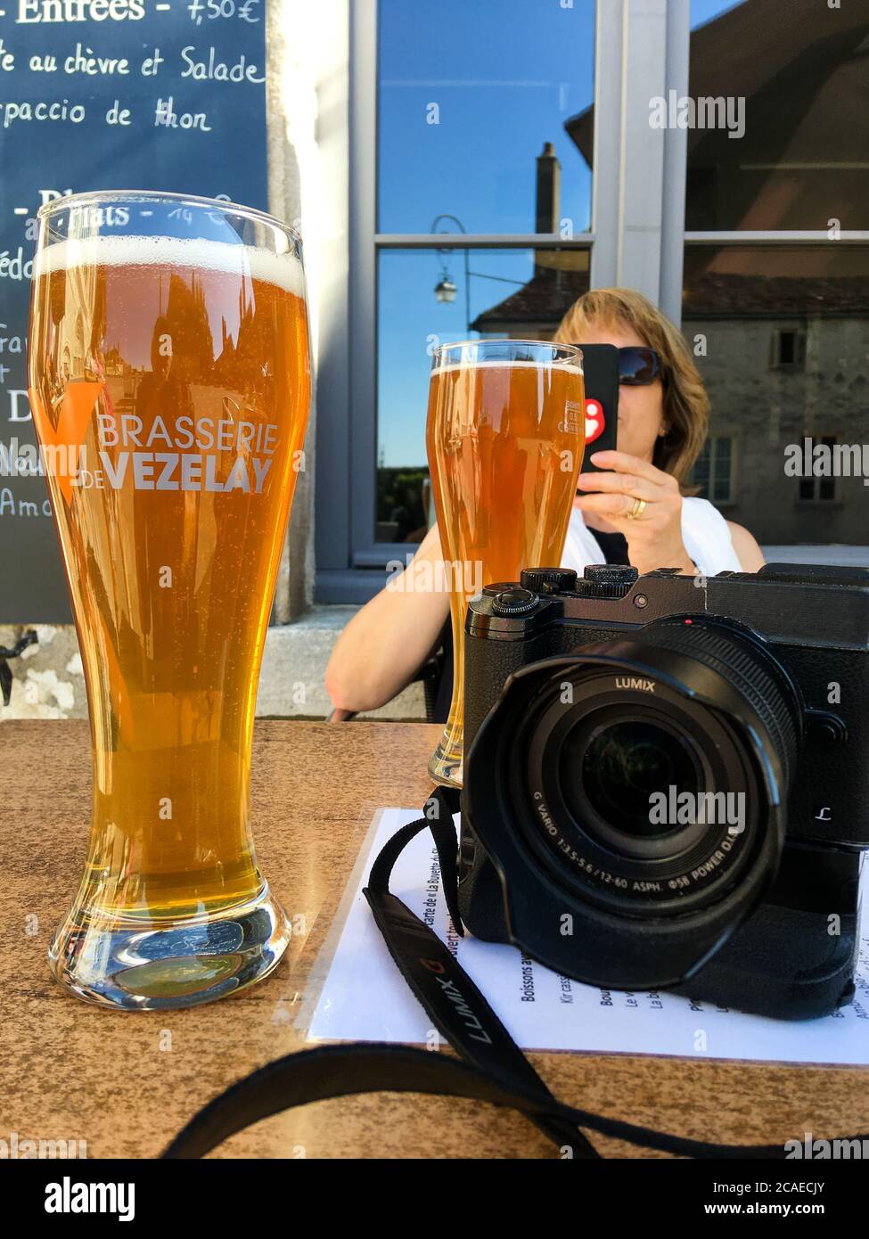 Digital camera, glasses of beer and good looking mature friend, illustration for a photographer's way of life, Vezelay, Yonne, Bourgogne Franche-Comté, France Stock Photo
