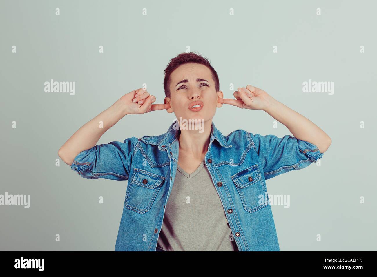 So loud. angry unhappy stressed woman covering her ears looking up stop
