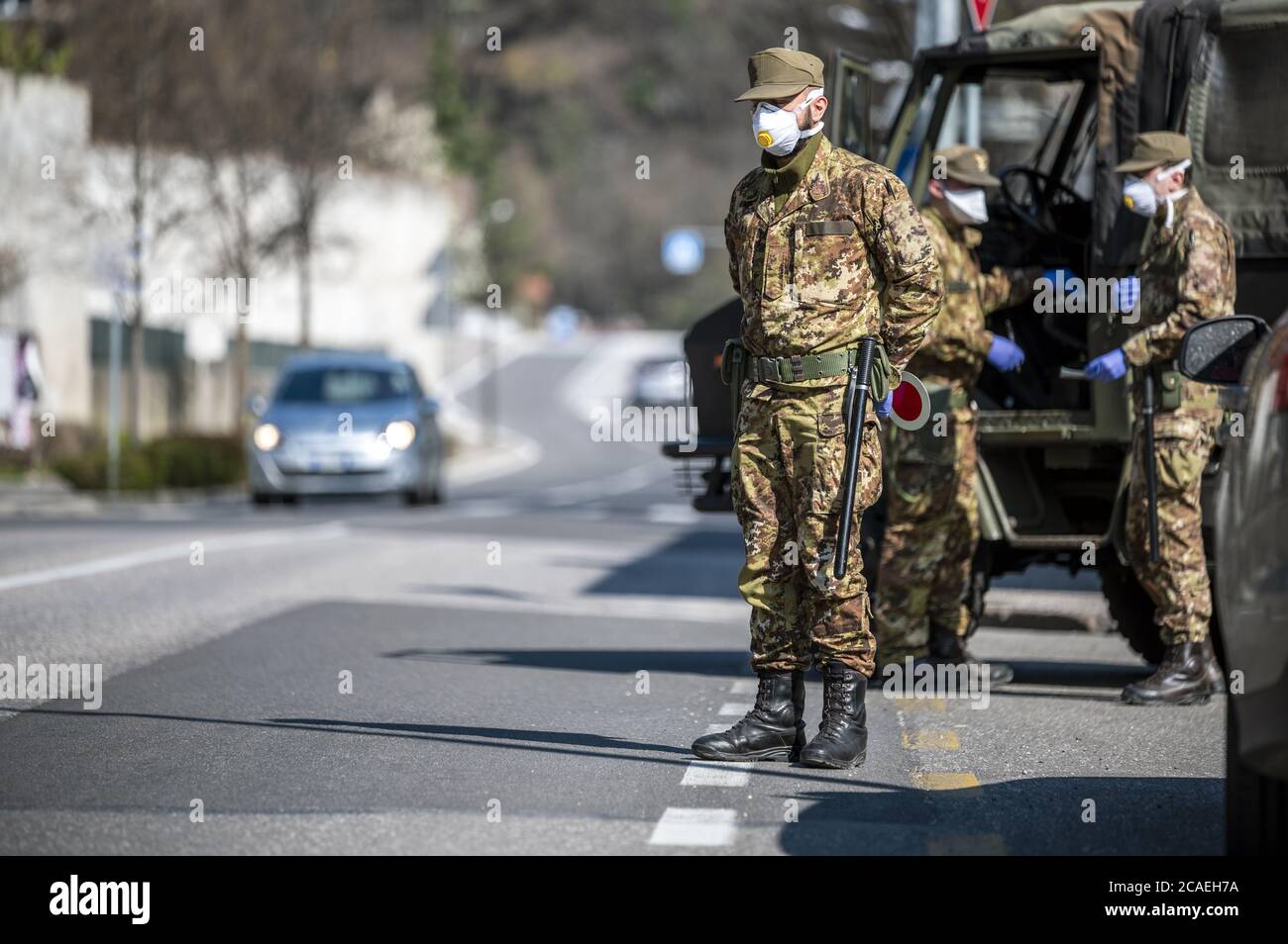Military soldier controls on the street. Security patrol with masks and gloves monitor passing motorists. Daily street control for the Covid-19. Stock Photo
