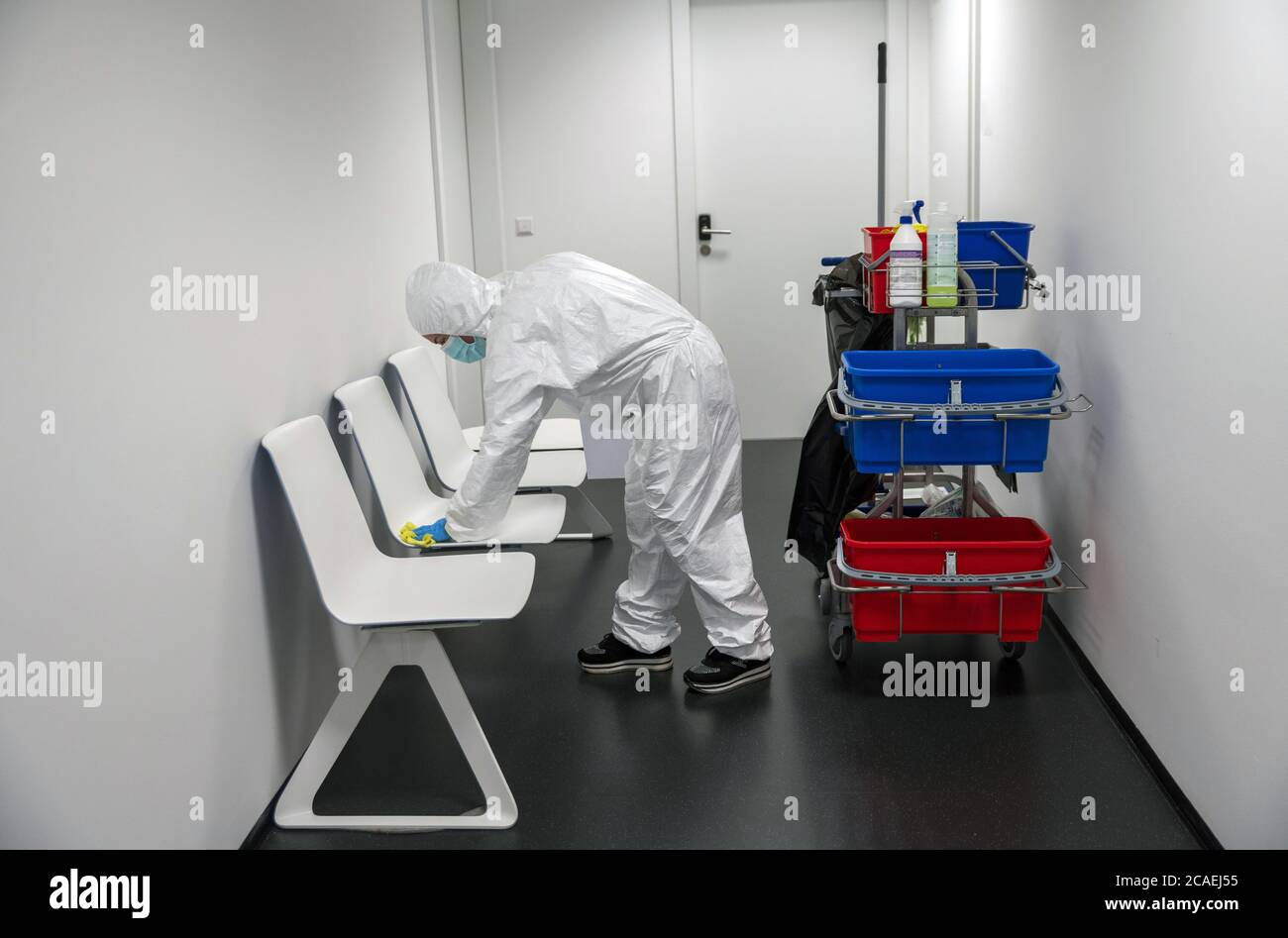 Alert Corona Virus or Covid-19. Cleaner with full protective suit, masks and gloves cleans, disinfects and sanitizes the waiting roorm and chairs. Stock Photo