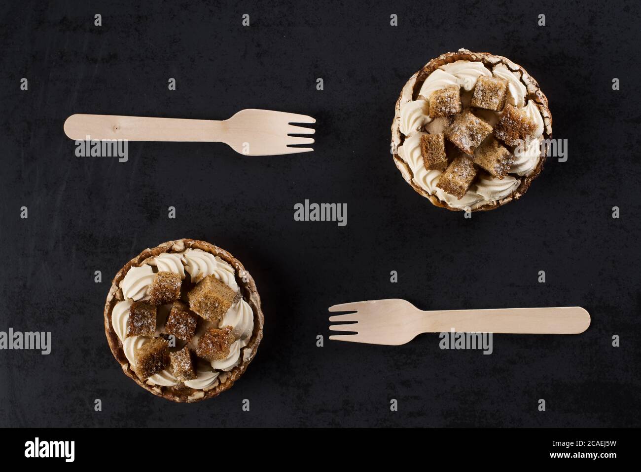 Two banofee high banana pie with wooden disposable fork against dark background Stock Photo