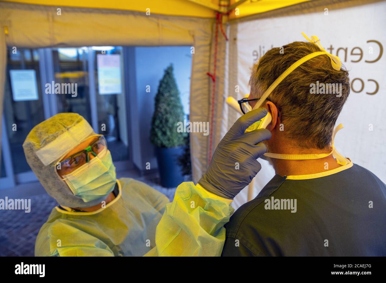 Alert pandemic Covid-19. Triage hospital field tent for the first AID for patient infected with Corona Virus. Doctor with checks the patient's fever. Stock Photo