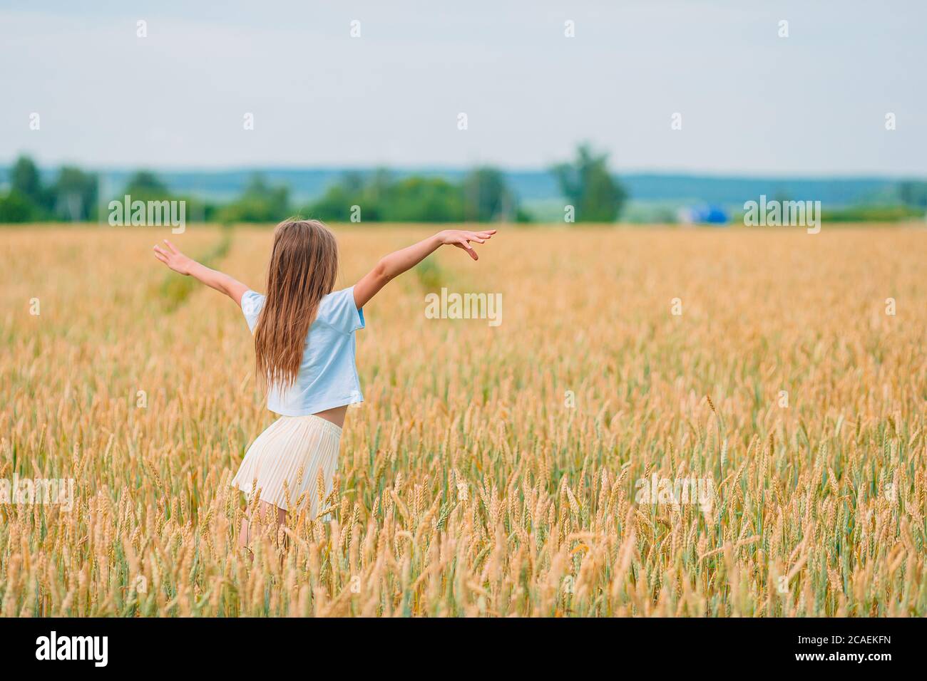 Happy little girl walking in golden fields of wheat Stock Photo - Alamy