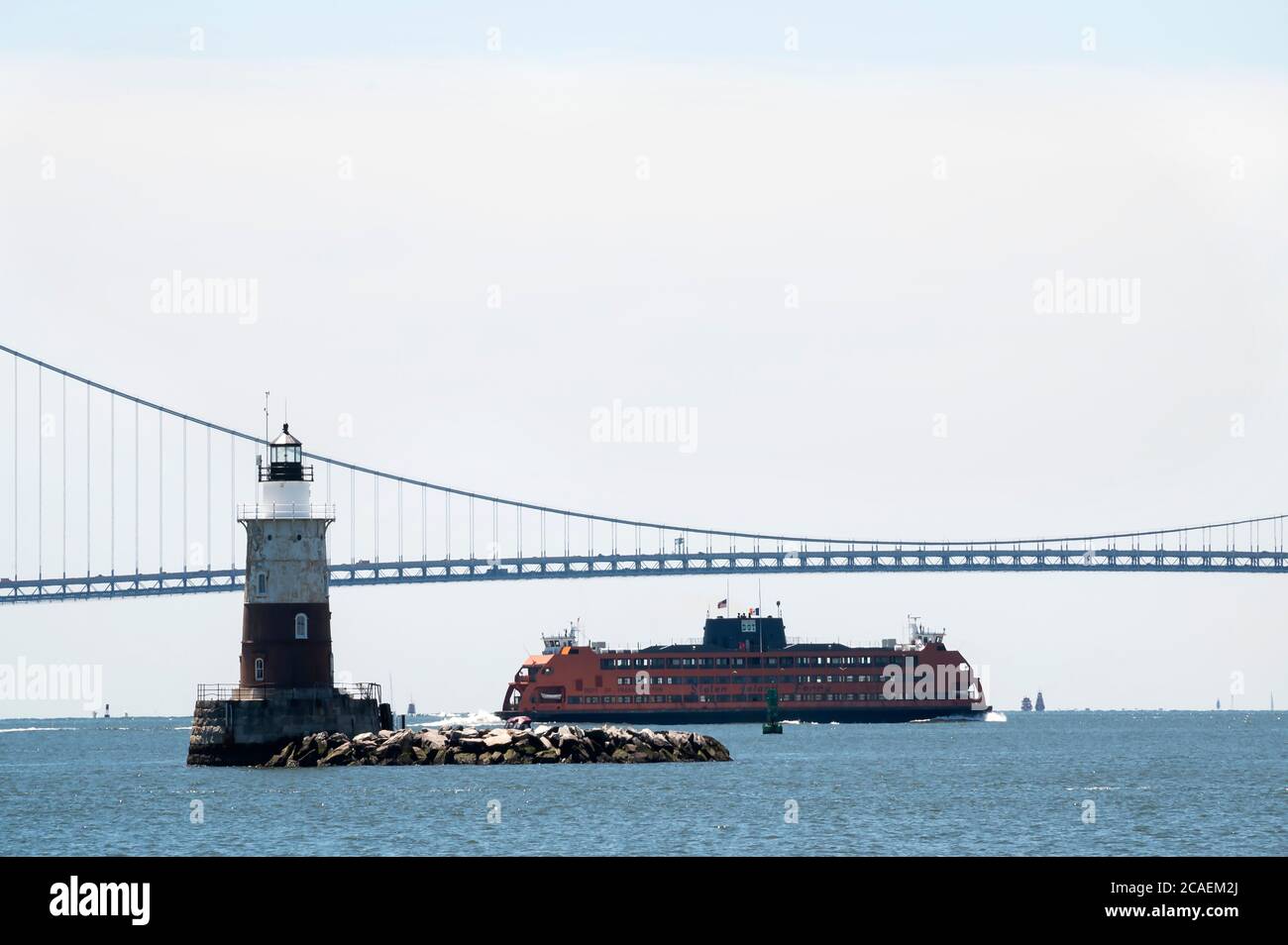 Staten Island ferry sails by lighthouse and under Verrazzano Bridge Stock Photo