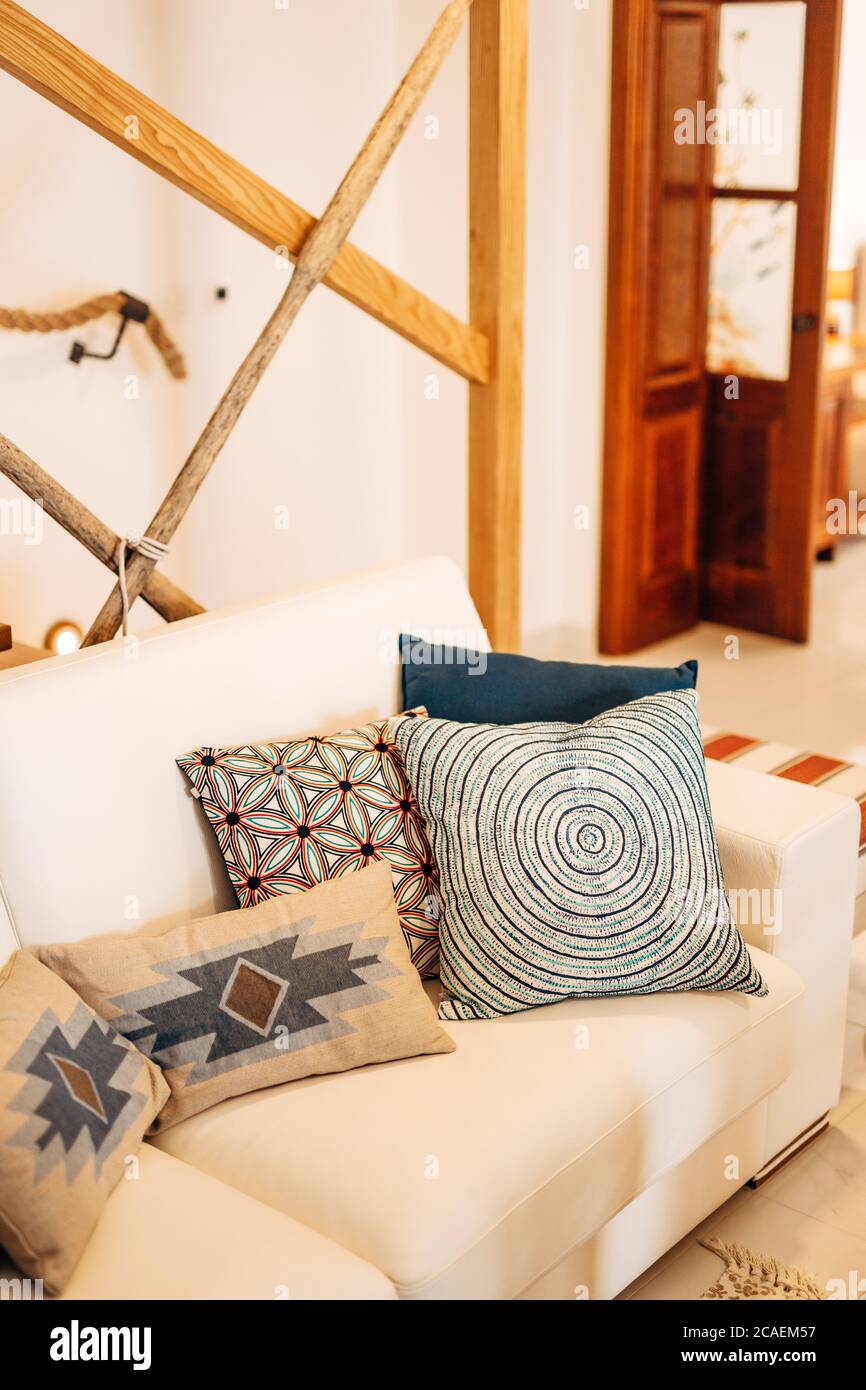 Pillows of different colors and sizes on a white sofa in a bright room. Stock Photo