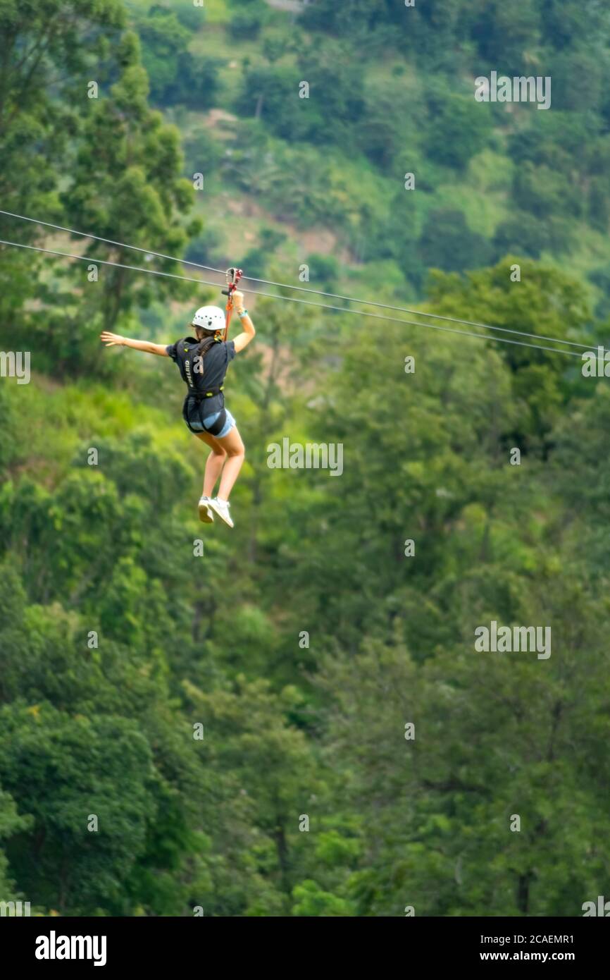 Young woman going on a zipline in the jungle. tree climbing in Sri Lanka. adventure , challenge and sport concept Stock Photo