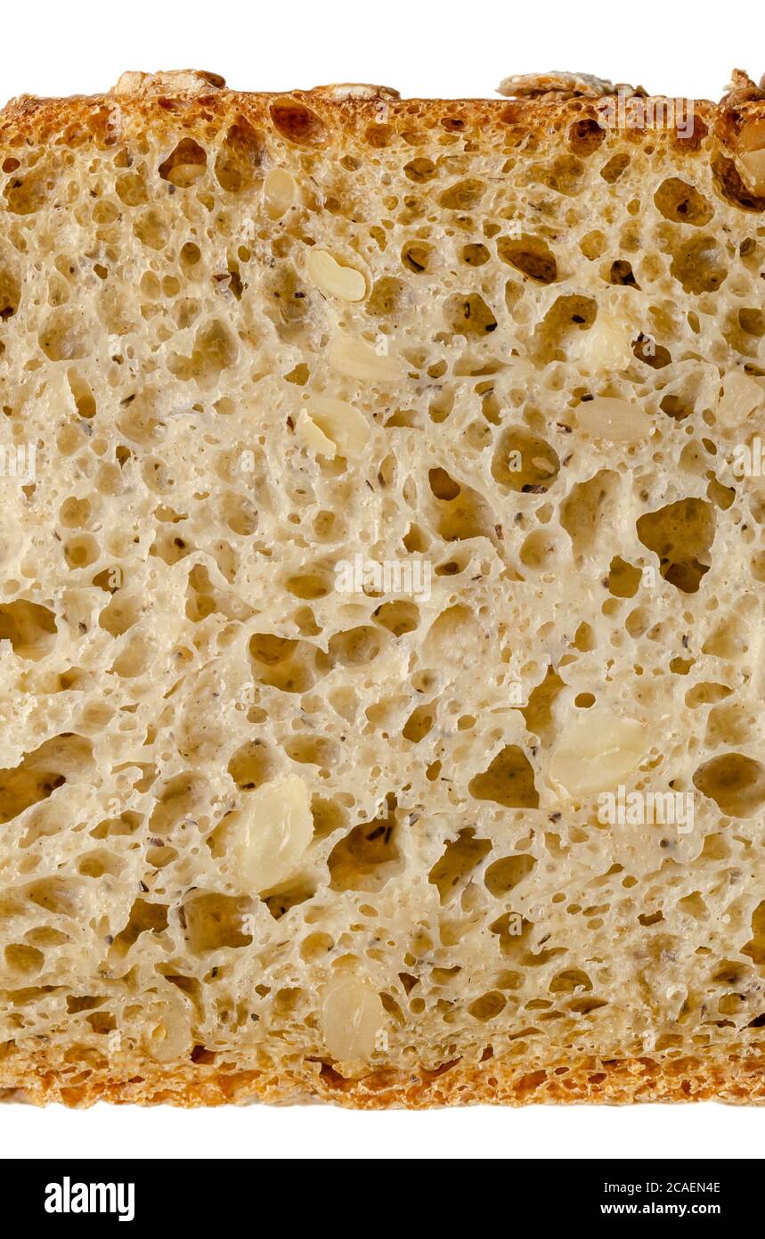 Slice of spelt bread, from above, close-up. Brown sourdough bread, mix of spelt flour, leaven, sunflower seeds and spices, baked in oven. Staple food. Stock Photo