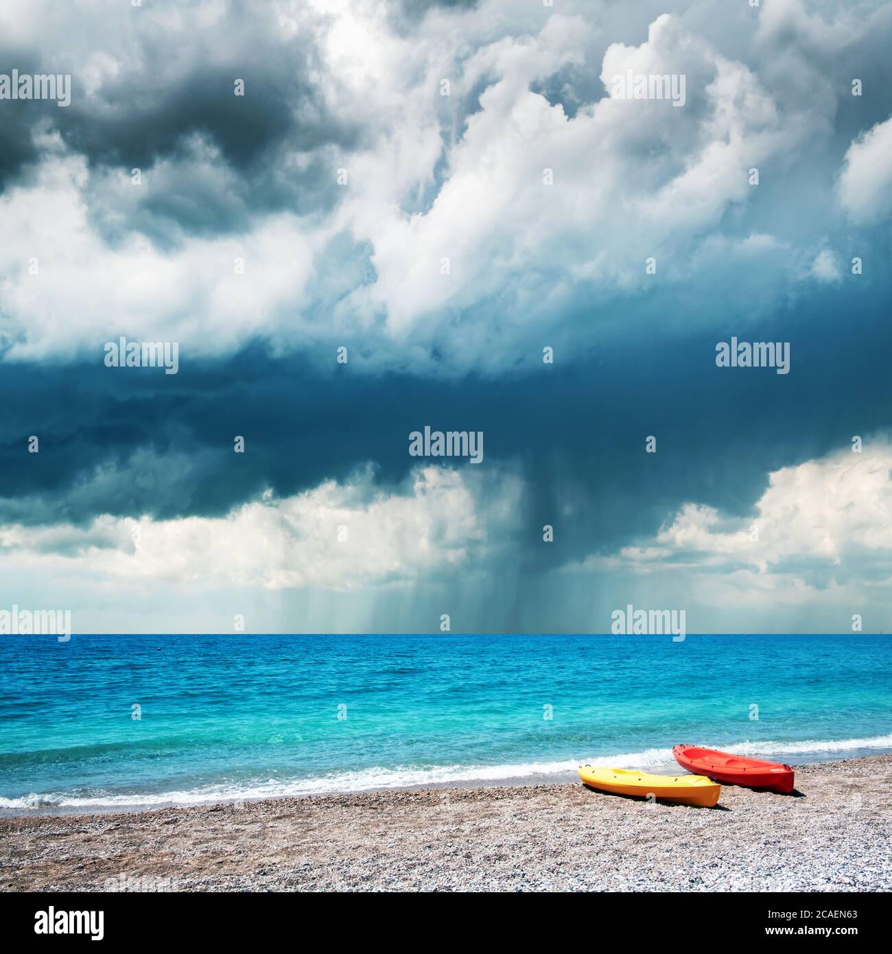 Two kayaks on sea edge. Dramatic storm clouds with rain on background. Summer time Stock Photo