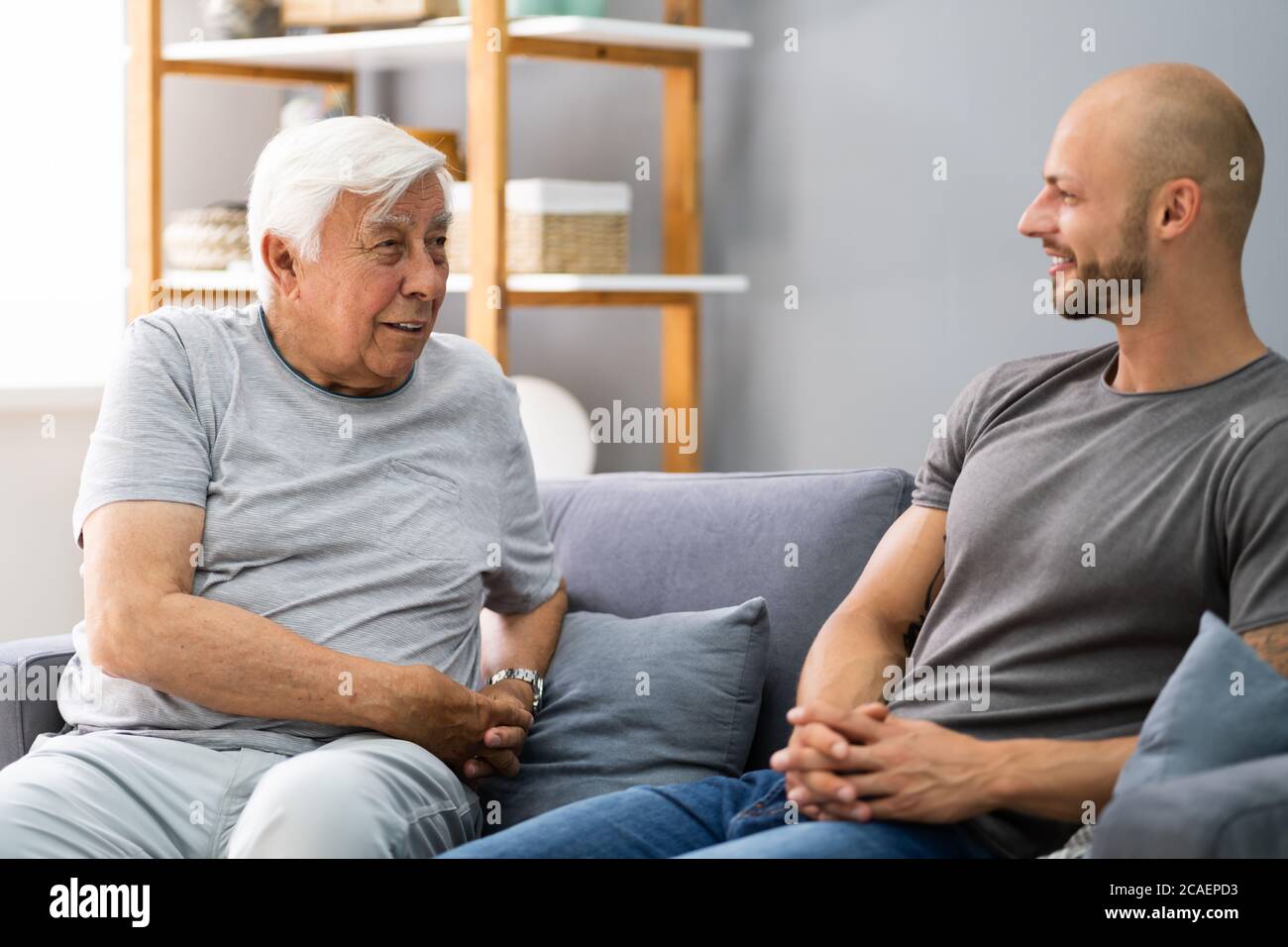 Grandpa Talking To His Grandson In Living Room Stock Photo